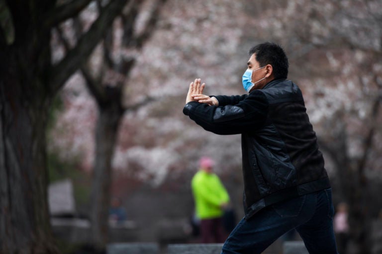Zhili Sun, practices tai chi by blooming cherry trees while wearing a mask  along the tidal basin in Washington. (Jacquelyn Martin/AP Photo)