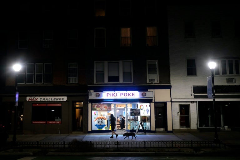 A man walks his dog on a mostly empty street before the start of a 10 p.m. curfew in Hoboken, N.J., Tuesday, March 17, 2020. (Seth Wenig/AP Photo)