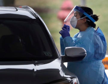 A medical staff member in protective gear administers a test for COVID-19 at a drive-through testing center in Paramus, N.J., Friday, March 20, 2020. (Seth Wenig/AP Photo)