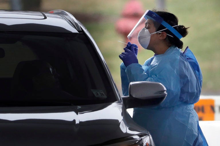 A medical staff member in protective gear administers a test for COVID-19 at a drive-through testing center in Paramus, N.J., Friday, March 20, 2020. (Seth Wenig/AP Photo)