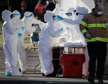 Staff in protective gear prepare to test people at a drive-through COVID-19 testing site at the PNC Bank Arts Center in Holmdel, N.J., Tuesday, March 24, 2020. (AP Photo/Seth Wenig)