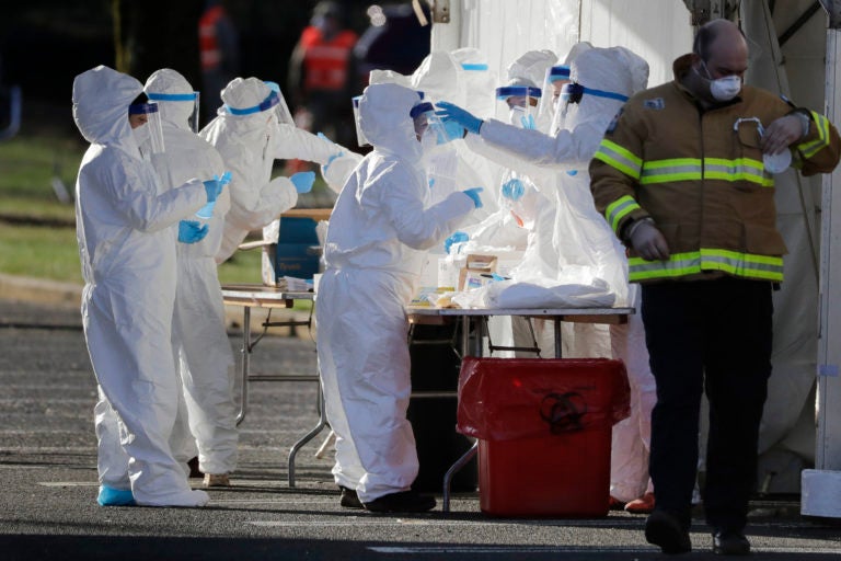 Staff in protective gear prepare to test people at a drive-through COVID-19 testing site at the PNC Bank Arts Center in Holmdel, N.J., Tuesday, March 24, 2020. (AP Photo/Seth Wenig)