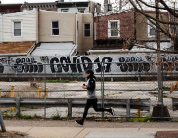 A jogger runs past a wall painted with the word 