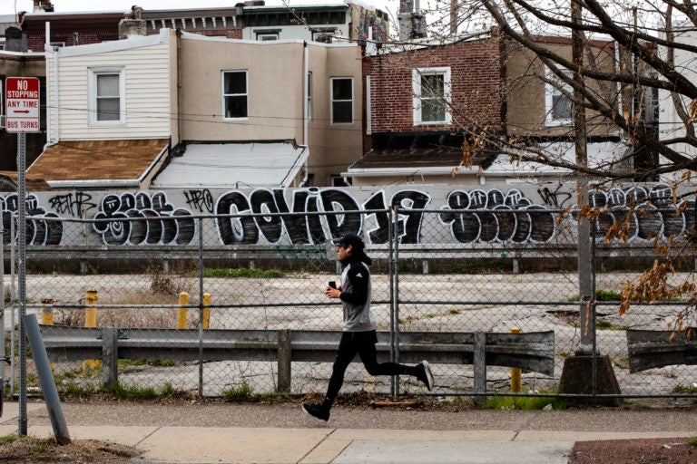 A jogger runs past a wall painted with the word 