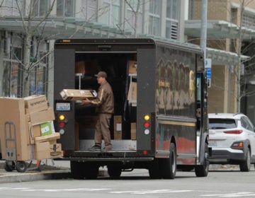 A United Parcel Service driver loads boxes during a delivery, Thursday, March 26, 2020, in downtown Seattle. UPS and other companies have been busy as people staying home under state-wide mandate amidst one of the worst outbreaks of the new coronavirus in the U.S. turn to online shopping to meet their needs. (AP Photo/Ted S. Warren)