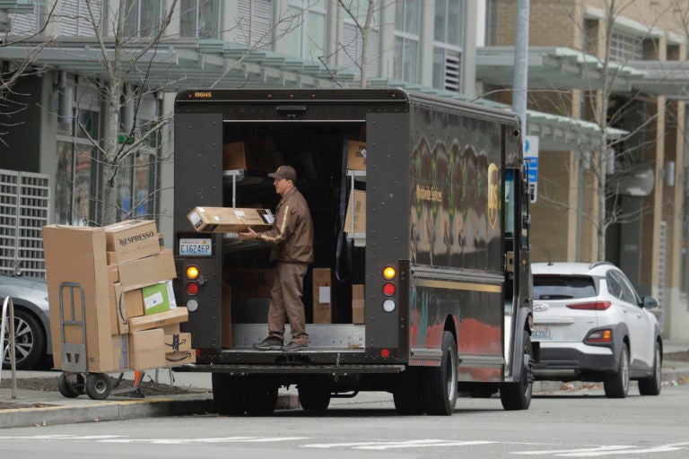 A United Parcel Service driver loads boxes during a delivery, Thursday, March 26, 2020, in downtown Seattle. UPS and other companies have been busy as people staying home under state-wide mandate amidst one of the worst outbreaks of the new coronavirus in the U.S. turn to online shopping to meet their needs. (AP Photo/Ted S. Warren)