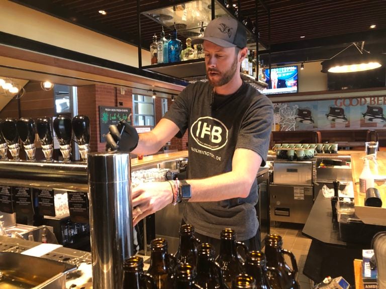 Dustin Mitchell fills up a growler for take-out orders at Iron Hill Brewery. (Cris Barrish/WHYY)