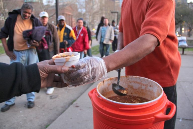 People line up for a meal in Pennypacker Park across from the Family Court building on Vine Street. (Emma Lee for WHYY)