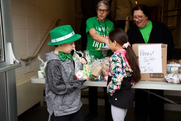 Gavin Holloman, 7, and Taylor Blake choose lunch and breakfast meals at the Bancroft School amid school shutdowns. (Kimberly Paynter/WHYY) 