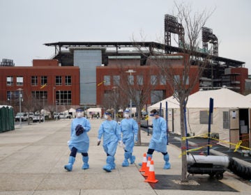 Philadelphia Medical Reserve Corps volunteers (from left) Megan Boyle, Marina Spitkovskaya, Jamie Huot, and Stephen Bonett, all of whom are nurses, walk to the swabbing tent as the city's coronavirus testing site prepared to open next to Citizens Bank Park in South Philadelphia on Friday, March 20, 2020. (Tim Tai/The Philadelphia Inquirer)
