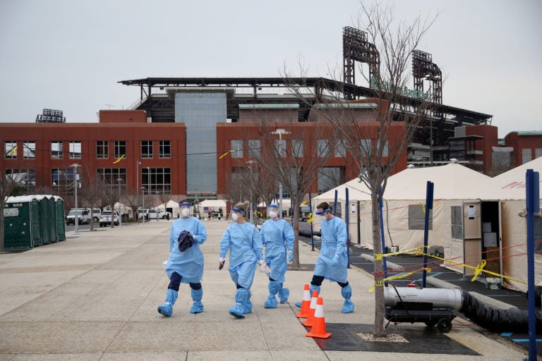 Philadelphia Medical Reserve Corps volunteers (from left) Megan Boyle, Marina Spitkovskaya, Jamie Huot, and Stephen Bonett, all of whom are nurses, walk to the swabbing tent as the city's coronavirus testing site prepared to open next to Citizens Bank Park in South Philadelphia on Friday, March 20, 2020. (Tim Tai/The Philadelphia Inquirer)