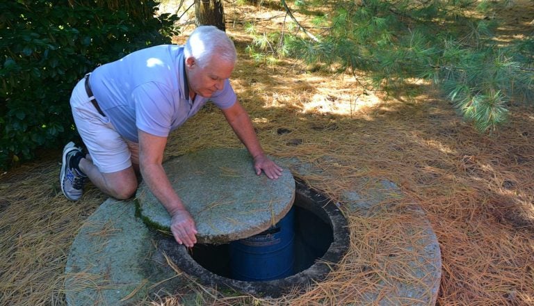 Jerry Solomon, of West Lampeter Township, rolls the stone slab that covers his private well water pump at the back of his home on Dec. 9, 2019. (Brett Sholtis/Transforming Health)