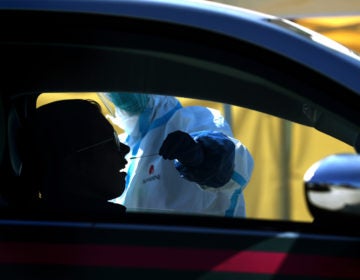After an initial verbal screening, one driver at a time gets a COVID-19 nasal swab test from a garbed health worker at a drive-up station in Daly City, Calif. (Justin Sullivan/Getty Images)