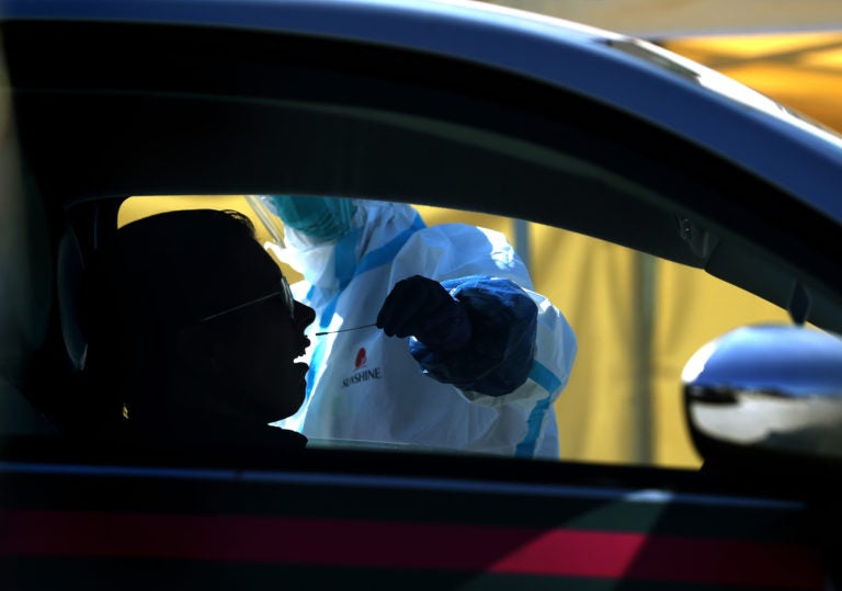 After an initial verbal screening, one driver at a time gets a COVID-19 nasal swab test from a garbed health worker at a drive-up station in Daly City, Calif. (Justin Sullivan/Getty Images)