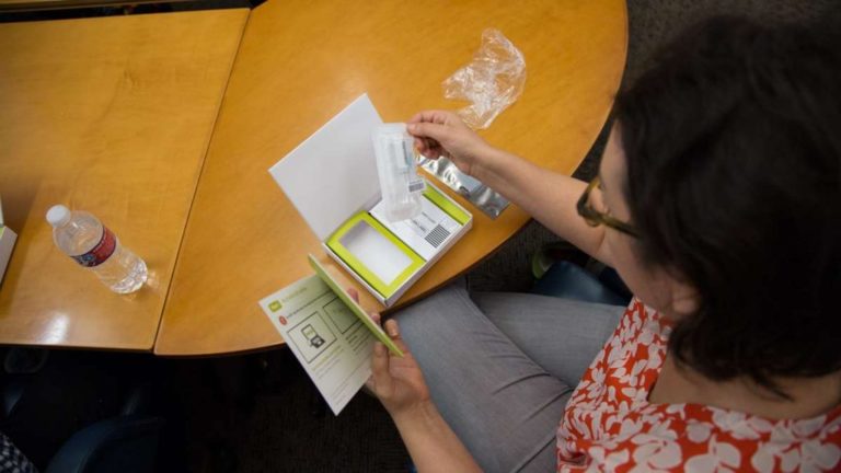 Dr. Allison Kolpas, a professor in the math department at West Chester University, opens her DNA testing packet. (Emily Cohen for WHYY)