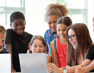 Students gathered around computers smiling