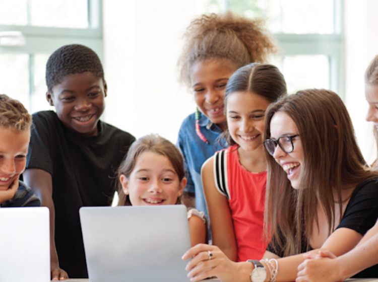 Students gathered around computers smiling