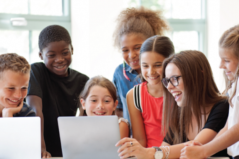 Students gathered around computers smiling