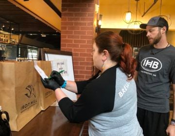 Moriah Guise and Dustin Mitchell check orders at Iron Hill Brewery. (Cris Barrish/WHYY)