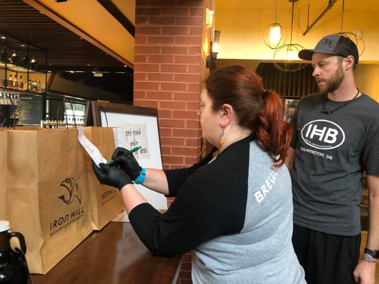 Moriah Guise and Dustin Mitchell check orders at Iron Hill Brewery. (Cris Barrish/WHYY)