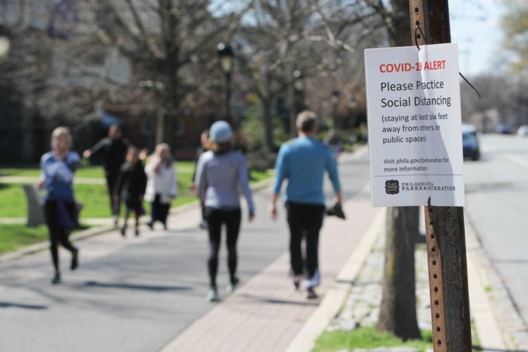 Signs posted along Philadelphia's Schuylkill River Trail caution users to keep six feet away from others to prevent the spread of COVID-19. (Emma Lee/WHYY)