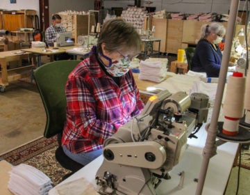 Luanne Albertson (center) sews masks at Eric and Christopher, LLC in Perkasie, Pa. (Emma Lee/WHYY)