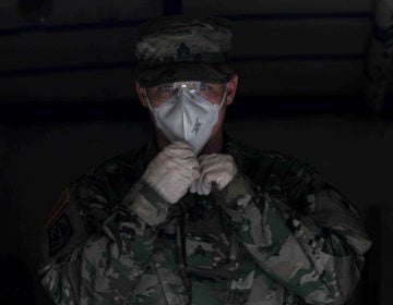 Delaware National Guard Sergeant Whitlock readies himself to deliver packaged food from a medium tactical vehicle on Wednesday, April 8, 2020, at Frederick Lodge Manufactured Home Community in Townsend, Del. (Saquan Stimpson for WHYY)