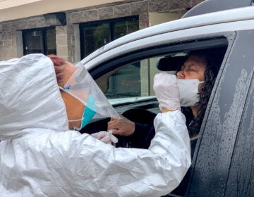 A Black doctor performs a free COVID-19 test in the parking lot of the West Philadelphia Seventh-day Adventist Church. (Christopher Norris for WHYY)
