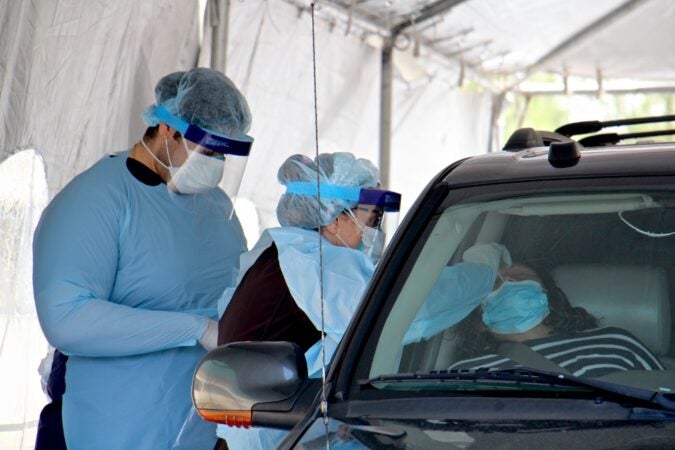 A medical technician performs a nasal swab on a patient at Camden's drive-through testing center at 2600 Mt. Ephraim Ave. (Emma Lee/WHYY)