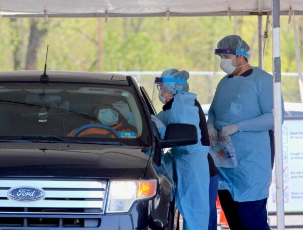 A medical technician performs a nasal swab on a patient at Camden's drive-through testing center at 2600 Mt. Ephraim Ave. (Emma Lee/WHYY)