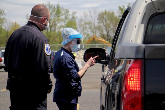 Nurse Practitioner Dodi Iannoco gives instructions to drive-up testing candidates as they arrive at the testing site at 2600 Mt. Ephraim Ave. in Camden, New Jersey. (Emma Lee/WHYY)