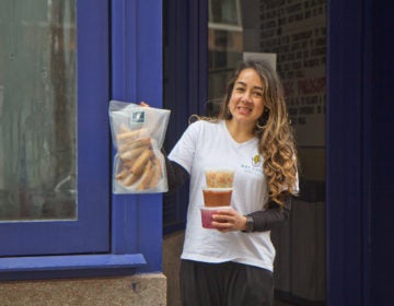 El Merkury owner Sofia Deleon holds taquitos, fried and rolled corn tortillas, and condiments. (Kimberly Paynter/WHYY)