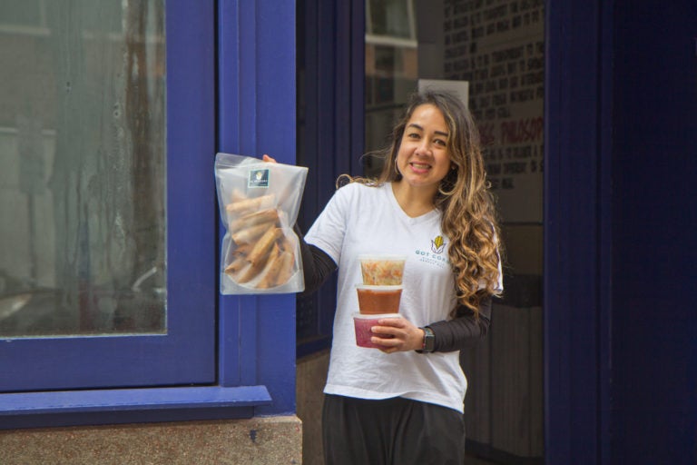 El Merkury owner Sofia Deleon holds taquitos, fried and rolled corn tortillas, and condiments. (Kimberly Paynter/WHYY)