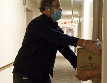 Volunteer Steve Huber drops off a box of food to a senior is public housing. (Kimberly Paynter/WHYY)