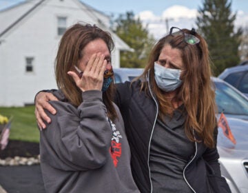 Tammy King (left) is comforted by her sister Michelle Rouco, both nurses, who were not allowed to see their father before he succumbed to COVID-19. (Kimberly Paynter/WHYY)