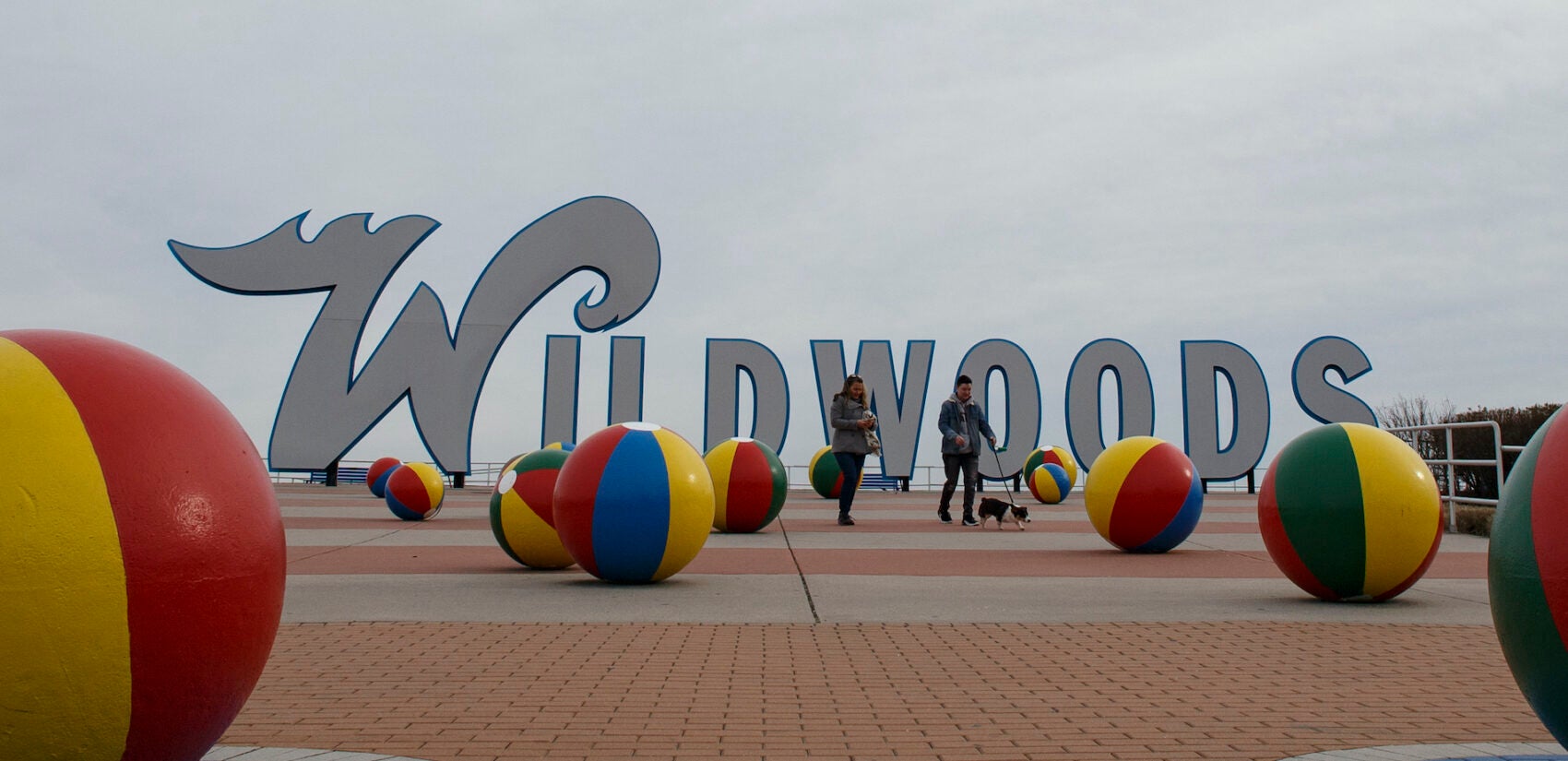 People walk a dog along the boardwalk in Wildwood