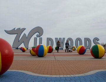 People walk a dog along the boardwalk in Wildwood