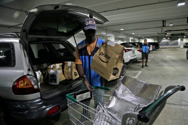 Samuel Diaz, a delivery worker for Amazon Prime, loads his vehicle with groceries from Whole Foods, Tuesday, March 31, 2020, in Miami, during the coronavirus pandemic. (Lynne Sladky/AP Photo)