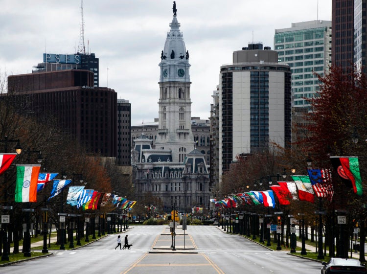 Flags from different countries blow in the wind as City Hall is visible in the background.