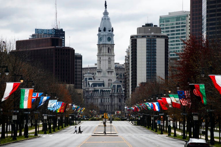 A couple walk their dog across the sparsely traveled Benjamin Franklin Parkway in Philadelphia, Friday, April 3, 2020. (Matt Rourke/AP Photo)