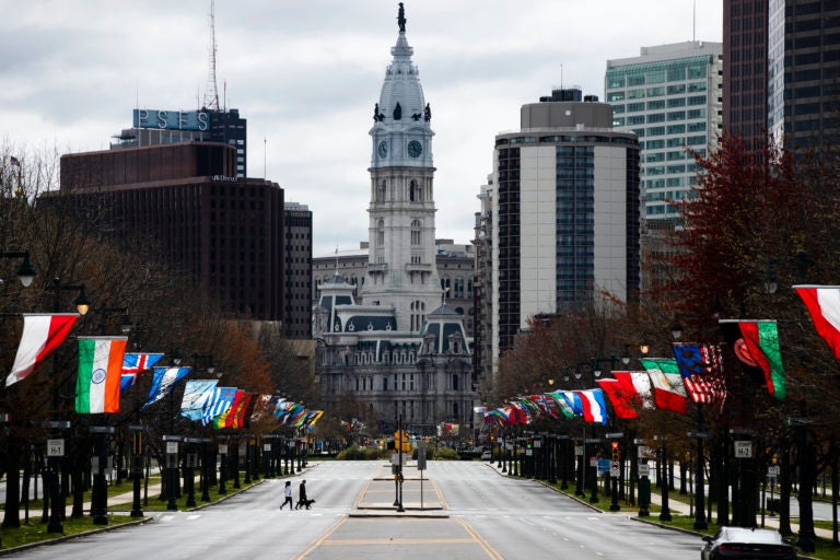 Flags from different countries blow in the wind as City Hall is visible in the background.