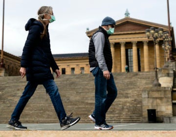 A couple in protective masks walk past the Philadelphia Museum of Art in Philadelphia, Friday, April 3, 2020. (Matt Rourke/AP Photo)