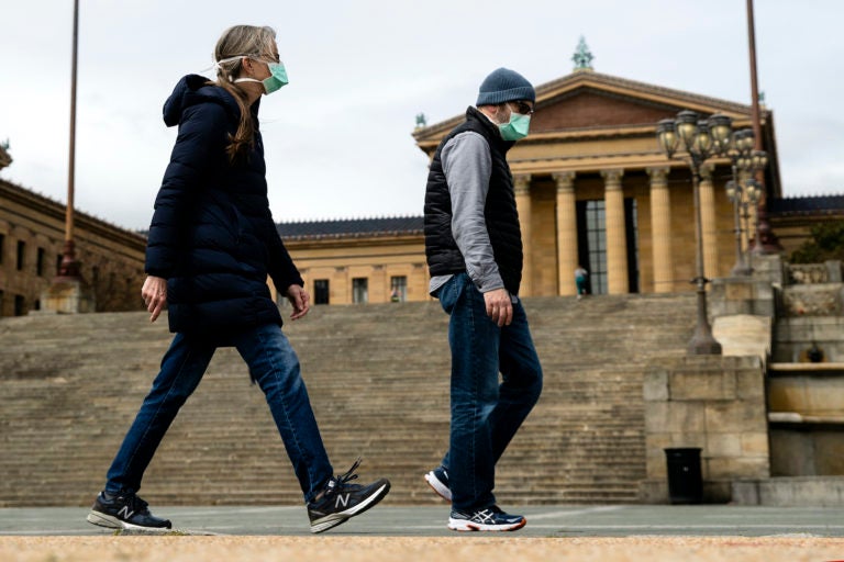 A couple in protective masks walk past the Philadelphia Museum of Art in Philadelphia, Friday, April 3, 2020. (Matt Rourke/AP Photo)