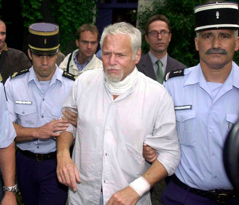 In this Thursday July 19, 2001 file photo, U.S. fugitive Ira Einhorn is taken away by French police in Champagne-Mouton, central France to be extradited to the United States. (Bob Edme/AP Photo)
