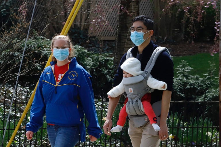 A couple out for walk wear protective masks on a warm afternoon in Pittsburgh, Sunday, April 5, 2020. (AP Photo/Gene J. Puskar)