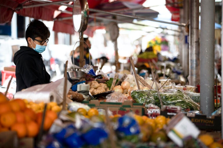 A vender wearing a face masks to protect against the spread of new coronavirus, works at a produce stand on South 9th Street in Italian Market neighborhood of Philadelphia, Thursday, April 9, 2020. (Matt Rourke/AP Photo)