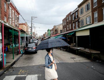 A shopper wearing a face mask to protect against the spread of the new coronavirus crosses South 9th Street in the Italian Market neighborhood of Philadelphia, Thursday, April 9, 2020. (AP Photo/Matt Rourke)