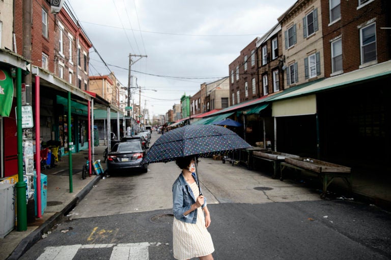 A shopper wearing a face mask to protect against the spread of the new coronavirus crosses South 9th Street in the Italian Market neighborhood of Philadelphia, Thursday, April 9, 2020. (AP Photo/Matt Rourke)