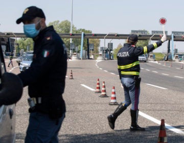 Police officers stop cars at the Melegnano highway barrier entrance, near Milan, Italy, Saturday, April 11, 2020. (Luca Bruno/AP Photo)