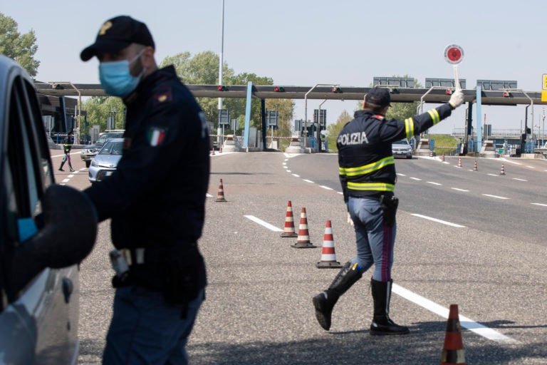 Police officers stop cars at the Melegnano highway barrier entrance, near Milan, Italy, Saturday, April 11, 2020. (Luca Bruno/AP Photo)